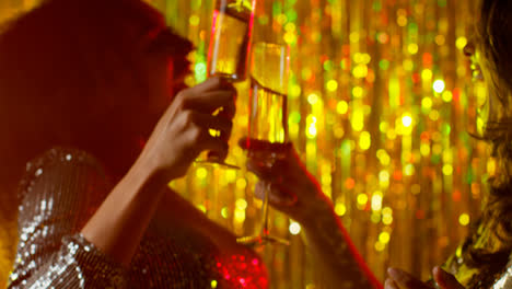 Close-Up-Of-Two-Women-Dancing-In-Nightclub-Or-Bar-Celebrating-Doing-Cheers-And-Drinking-Alcohol-With-Sparkling-Lights-3